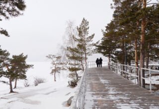 Заснеженное озеро Аулиеколь, дорожки по берегу, скалы и камни, скульптуры.