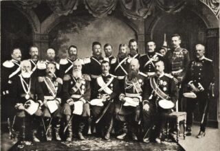 Августейший атаман со свитою среди сибирских казаков. г. Омск, 15 июля 1891 г. На снимке в первом ряду в центре сидит Государь Цесаревич Николай Александрович, слева сидит Степной генерал-губернатор Максим Антонович Таубе, за правым плечом Цесаревича стоит атаман 1-го военного отдела Сибирского казачьего войска в звании генерал-лейтенанта Николай Алексеевич Симонов; во втором ряду третьим слева стоит полковник Георгий Ефремович Катанаев; второй справа – полковник Иван Семенович Волков, председатель Войскового правления Семиреченского казачьего войска; восьмым – полковник Петр Сергеевич Щербаков, командир 1-го Семиреченского казачьего полка.