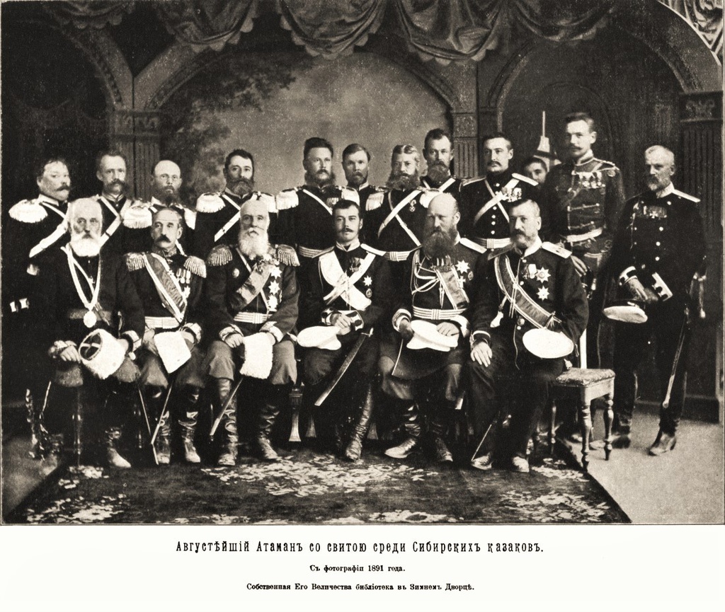 Августейший атаман со свитою среди сибирских казаков. г. Омск, 15 июля 1891 г. На снимке в первом ряду в центре сидит Государь Цесаревич Николай Александрович, слева сидит Степной генерал-губернатор Максим Антонович Таубе, за правым плечом Цесаревича стоит атаман 1-го военного отдела Сибирского казачьего войска в звании генерал-лейтенанта Николай Алексеевич Симонов; во втором ряду третьим слева стоит полковник Георгий Ефремович Катанаев; второй справа – полковник Иван Семенович Волков, председатель Войскового правления Семиреченского казачьего войска; восьмым – полковник Петр Сергеевич Щербаков, командир 1-го Семиреченского казачьего полка.